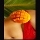 Cut mango half balanced on the hip of a person in red lace underwear